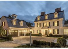 a large white house with lots of windows and lights on it's front porch