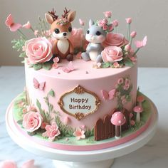 a pink birthday cake decorated with animals and flowers