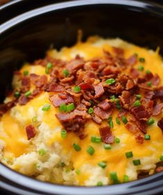 a crock pot filled with mashed potatoes topped with bacon and chopped green onions