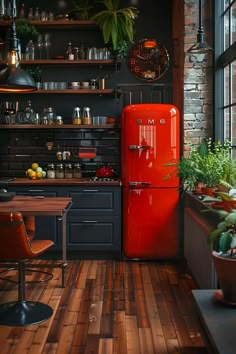 a red refrigerator sitting in the middle of a kitchen next to a table and chairs