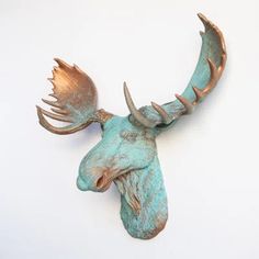 a metal moose head mounted to the wall with copper colored antlers on it's back