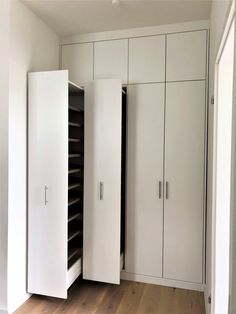 an empty room with white cupboards and wood flooring