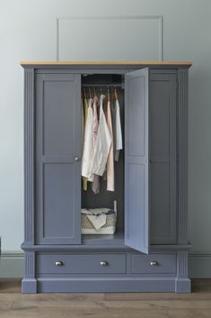 a blue armoire with clothes hanging on it