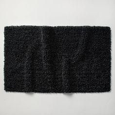 a black rug is laying on the floor next to a white wall with an object in it