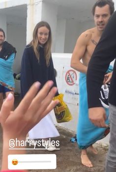 a group of people standing next to each other in front of a building with no shirt on