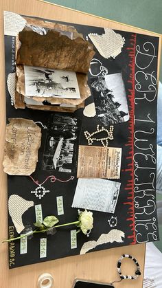 a table topped with lots of papers and other things on top of it, next to a cell phone