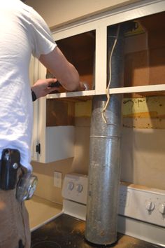 a man is working on an oven in the kitchen with no door or window frames