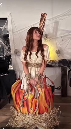 a woman in a costume is standing next to a fire