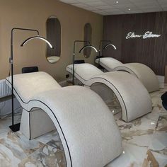 three white curved beds sitting on top of a marble floor in front of a wall