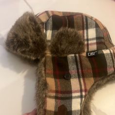 someone is holding a plaid hat with fur on it