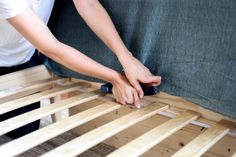 a person laying on top of a wooden bed frame with their hands over the slats