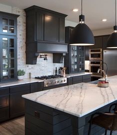 a large kitchen with black cabinets and marble counter tops, along with stainless steel appliances