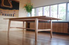 a wooden table sitting on top of a hard wood floor next to a large window