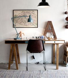 a wooden desk topped with a chair next to a painting