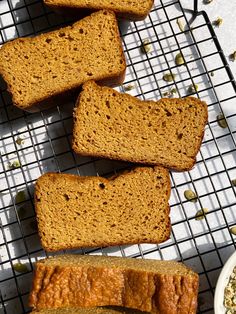 several slices of bread sitting on top of a cooling rack next to a bowl of seeds