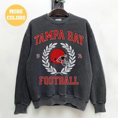 a sweatshirt with the words tampa bay on it and a football helmet hanging from a hook