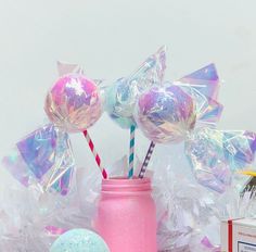 a pink mason jar filled with lollipops next to other candy and confetti