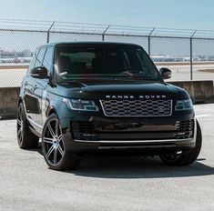 a black range rover parked in front of a fenced off area with no cars