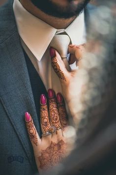 a man wearing a suit and tie with henna on his hands