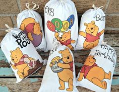 four winnie the pooh birthday bags on a bench