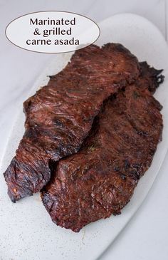 two pieces of steak on a white plate with a thought bubble above it that says marinated and grilled came asada