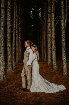 a bride and groom standing in the middle of a pine forest at their wedding day