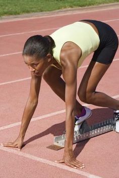 a woman is bent over on a track with a scale in front of her as she prepares to run