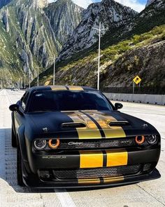 a black and yellow striped car parked in front of a mountain range with mountains in the background