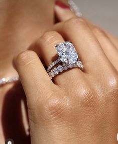 a woman's hand with a diamond ring on top of her finger and an engagement band