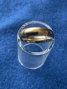 two gold wedding rings sitting on top of a blue carpeted floor in front of a blue background