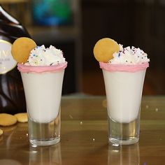 two glasses filled with whipped cream and sprinkles on top of a table