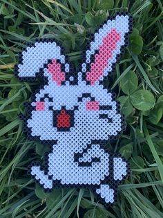 a cross - stitch bunny is sitting in the grass