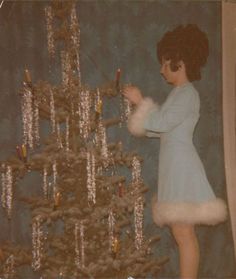 a woman decorating a christmas tree with candles