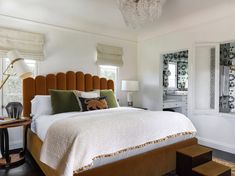 a bedroom with a bed, mirror and stools in the corner next to each other