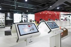 two computer monitors sitting on top of a counter in front of a red and white wall