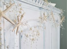 starfishs and pearls hang from the side of a white painted door in an old - fashioned room