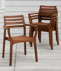 three wooden chairs sitting next to each other on top of a wooden floor near a white house