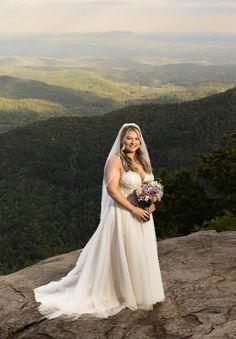 a woman in a wedding dress standing on top of a mountain