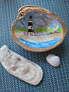 there is a small bowl with a painting on it and a seashell next to it