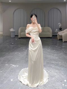 a woman in a white dress is holding her face up to the side while standing on a marble floor