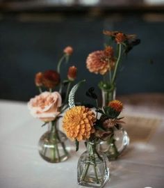 three glass vases with flowers in them on a table