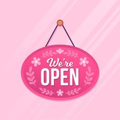 a pink sign that says we're open hanging from a hook on a wall