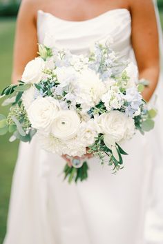 a bride holding a bouquet of white and blue flowers