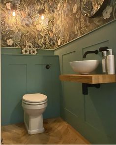 a white toilet sitting in a bathroom next to a wooden shelf with a bowl on it