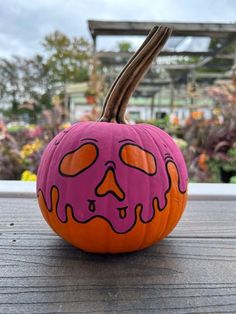 a painted pumpkin sitting on top of a wooden table