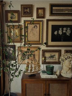 a living room with pictures on the wall and a potted plant next to it