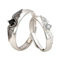 two white gold wedding rings with black diamonds on each one and a bat motif in the middle