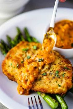 chicken parmesan crusted with vodka sauce on top of green asparagus