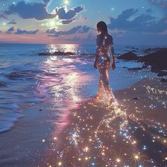 a woman standing on top of a sandy beach next to the ocean at night time