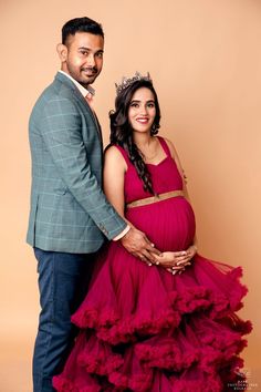 a pregnant woman in a red dress poses with her husband